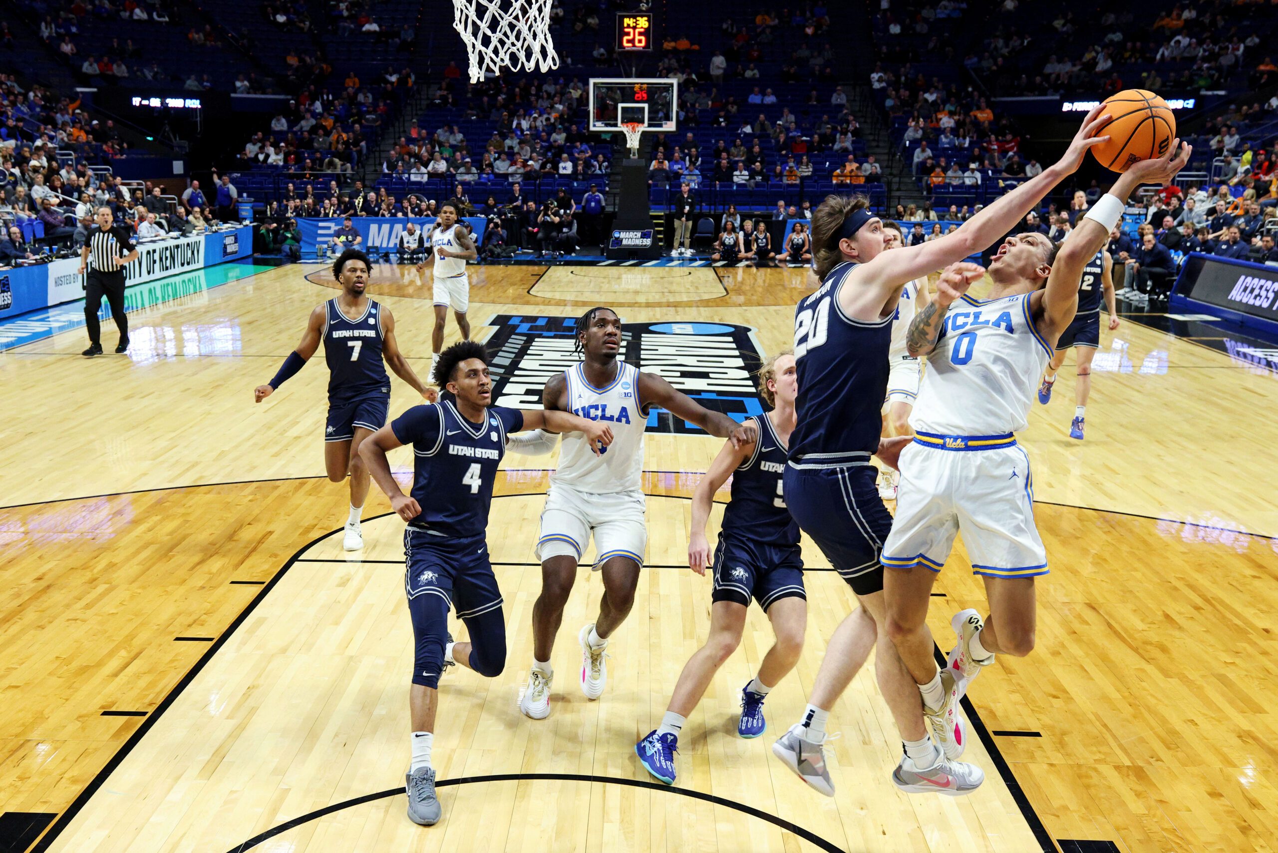 Mar 20, 2025; Lexington, KY, USA;  Utah State Aggies center Isaac Johnson (20) blocks the shot of UCLA Bruins guard Kobe Johnson (0) during the second half in the first round of the NCAA Tournament at Rupp Arena. Mandatory Credit: Jordan Prather-Imagn Images