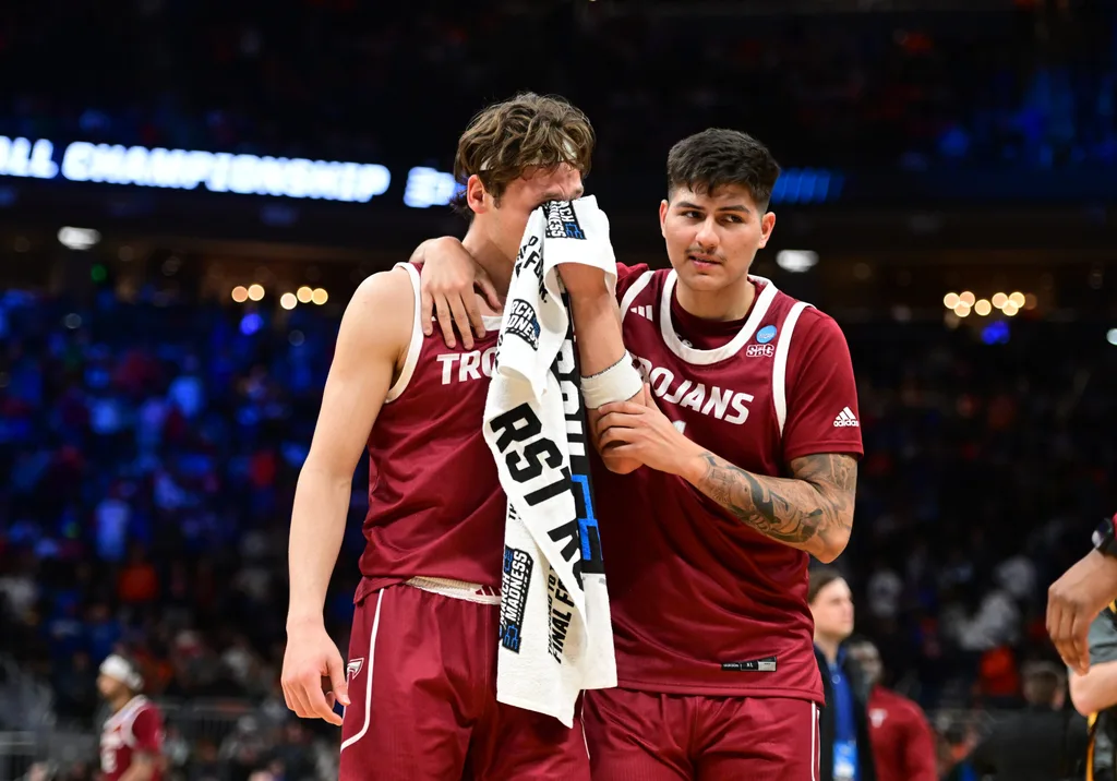 Mar 21, 2025; Milwaukee, WI, USA; Troy Trojans forward Thomas Dowd (1) holds their face in a towel as forward Victor Valdes (11) hugs them following a loss to the Kentucky Wildcats at Fiserv Forum. Mandatory Credit: Benny Sieu-Imagn Images