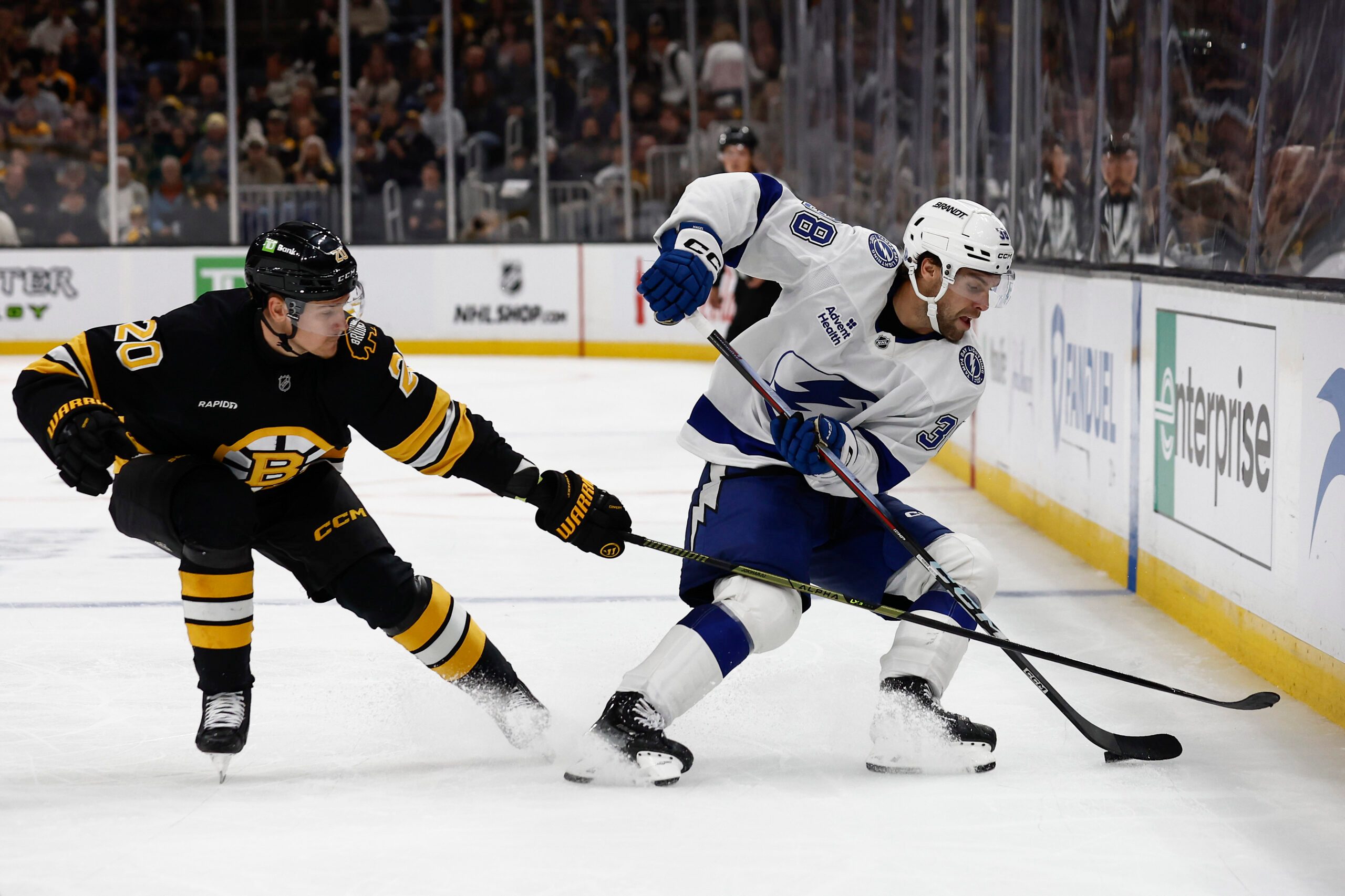 Oct 13, 2025; Boston, Massachusetts, USA; Tampa Bay Lightning left wing Brandon Hagel (38) spins away from Boston Bruins defenseman Henri Jokiharju (20) during the third period at TD Garden. Mandatory Credit: Winslow Townson-Imagn Images