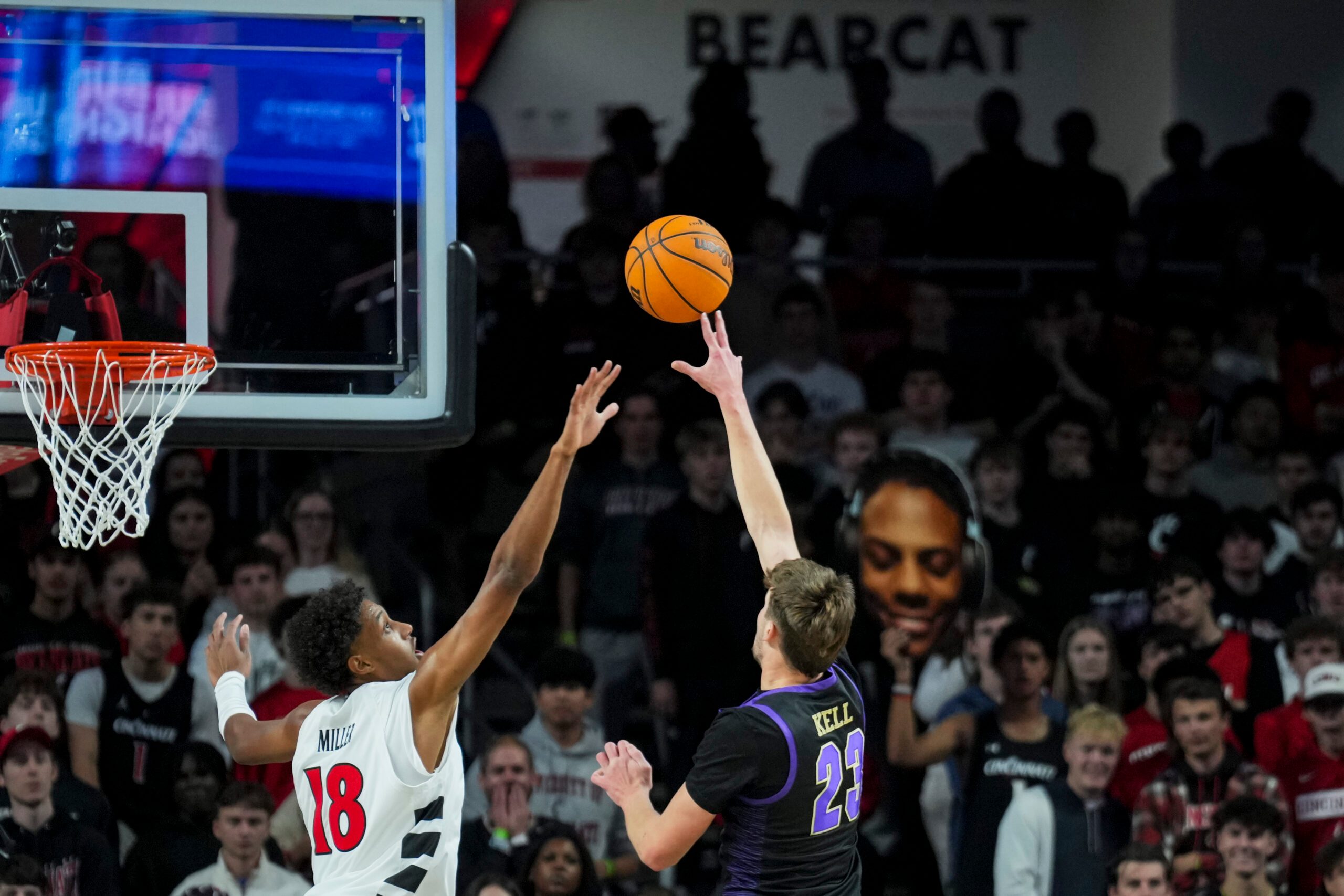 Nov 3, 2025; Cincinnati, Ohio, USA;  Western Carolina Catamounts forward Marcus Kell (23) shoots against Cincinnati Bearcats forward Baba Miller (18) in the first half at Fifth Third Arena. Mandatory Credit: Aaron Doster-Imagn Images