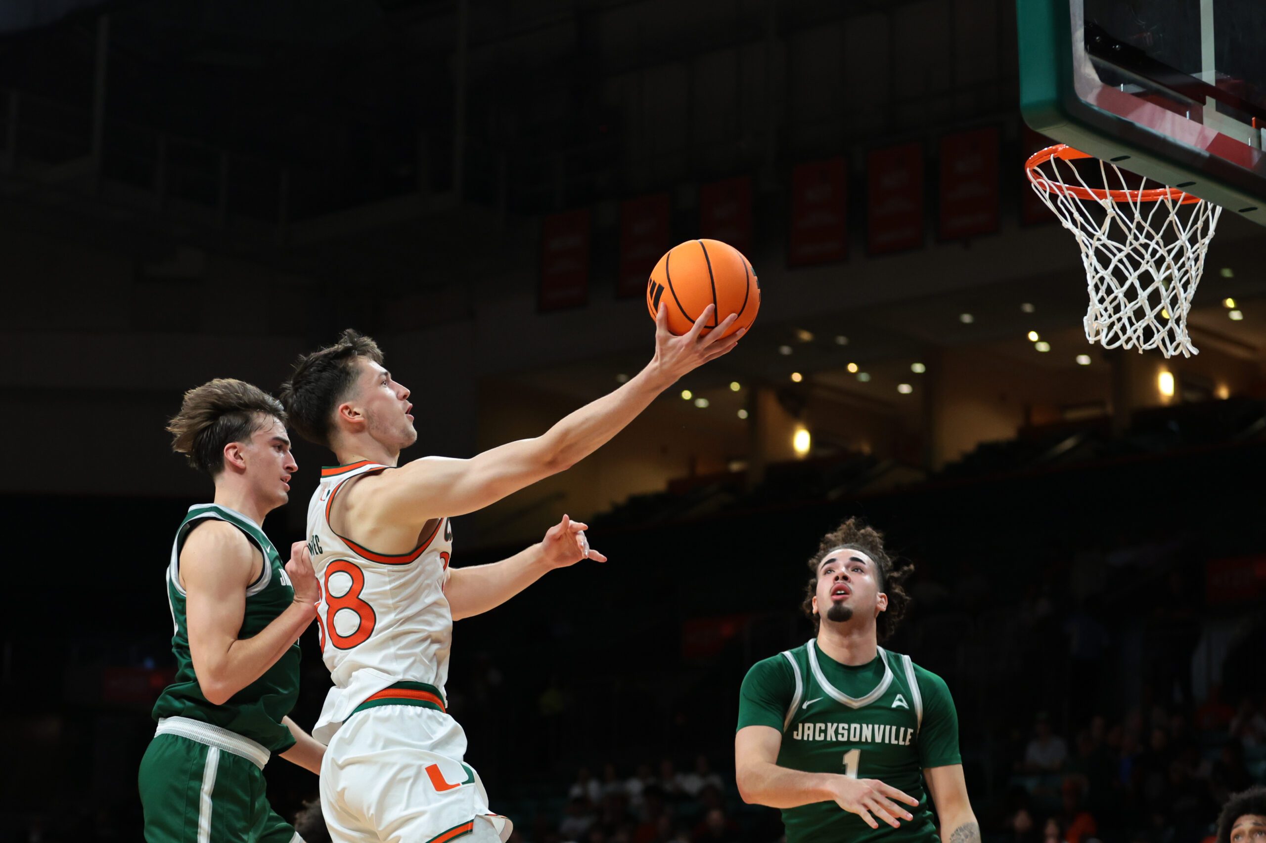 Nov 3, 2025; Coral Gables, Florida, USA; Miami Hurricanes forward Timotej Malovec (88) drives to the basket against Jacksonville Dolphins guard Hayden Wood (8) during the first half at Watsco Center. Mandatory Credit: Sam Navarro-Imagn Images