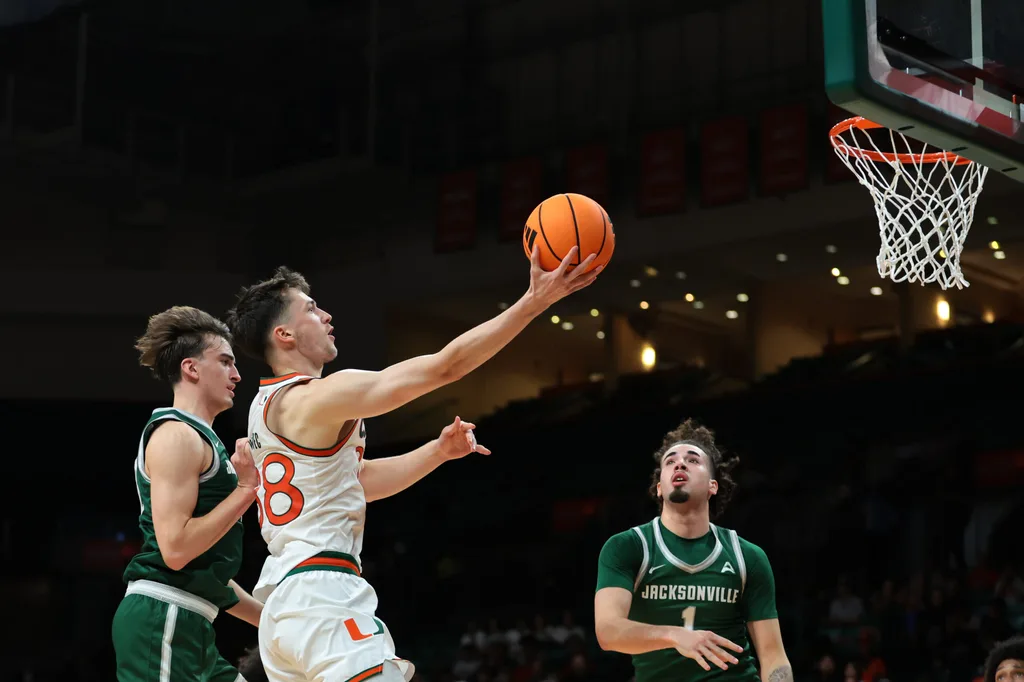 Nov 3, 2025; Coral Gables, Florida, USA; Miami Hurricanes forward Timotej Malovec (88) drives to the basket against Jacksonville Dolphins guard Hayden Wood (8) during the first half at Watsco Center. Mandatory Credit: Sam Navarro-Imagn Images