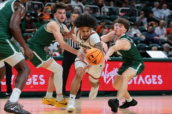 Nov 3, 2025; Coral Gables, Florida, USA; Miami Hurricanes guard Tre Donaldson (center) drives to the basket against Jacksonville Dolphins guard Hayden Wood (left) and guard Evan Sterck (34) during the second half at Watsco Center. Mandatory Credit: Sam Navarro-Imagn Images
