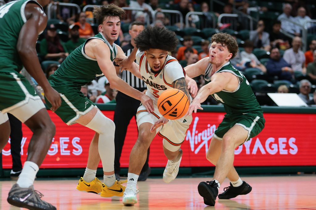 Nov 3, 2025; Coral Gables, Florida, USA; Miami Hurricanes guard Tre Donaldson (center) drives to the basket against Jacksonville Dolphins guard Hayden Wood (left) and guard Evan Sterck (34) during the second half at Watsco Center. Mandatory Credit: Sam Navarro-Imagn Images