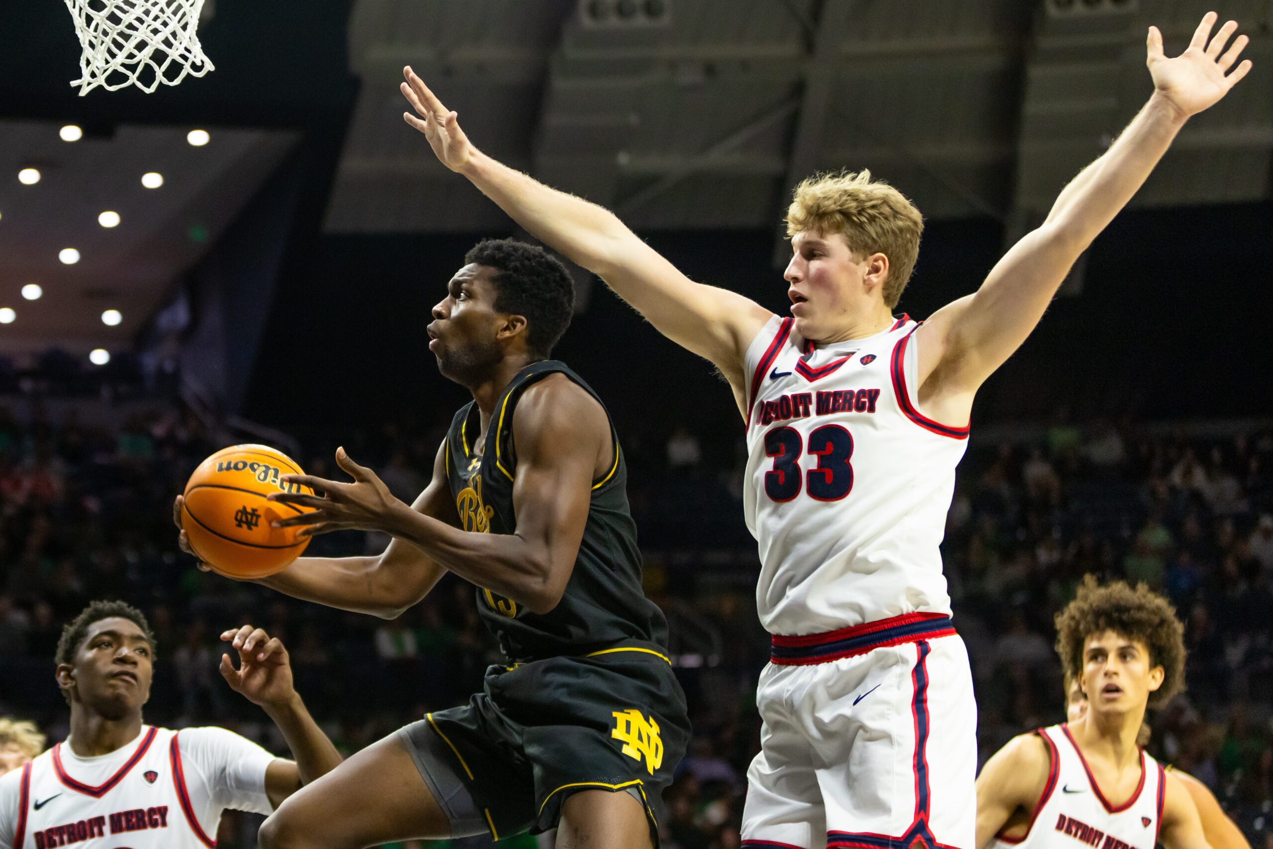 Nov 7, 2025; South Bend, Indiana, USA; Notre Dame Fighting Irish guard Sir Mohammed (13) drives past Detroit Mercy Titans guard TJ Nadeau (33) during the second half at Purcell Pavilion at the Joyce Center. Mandatory Credit: Michael Caterina-Imagn Images