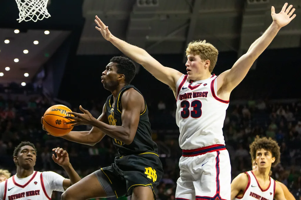 Nov 7, 2025; South Bend, Indiana, USA; Notre Dame Fighting Irish guard Sir Mohammed (13) drives past Detroit Mercy Titans guard TJ Nadeau (33) during the second half at Purcell Pavilion at the Joyce Center. Mandatory Credit: Michael Caterina-Imagn Images