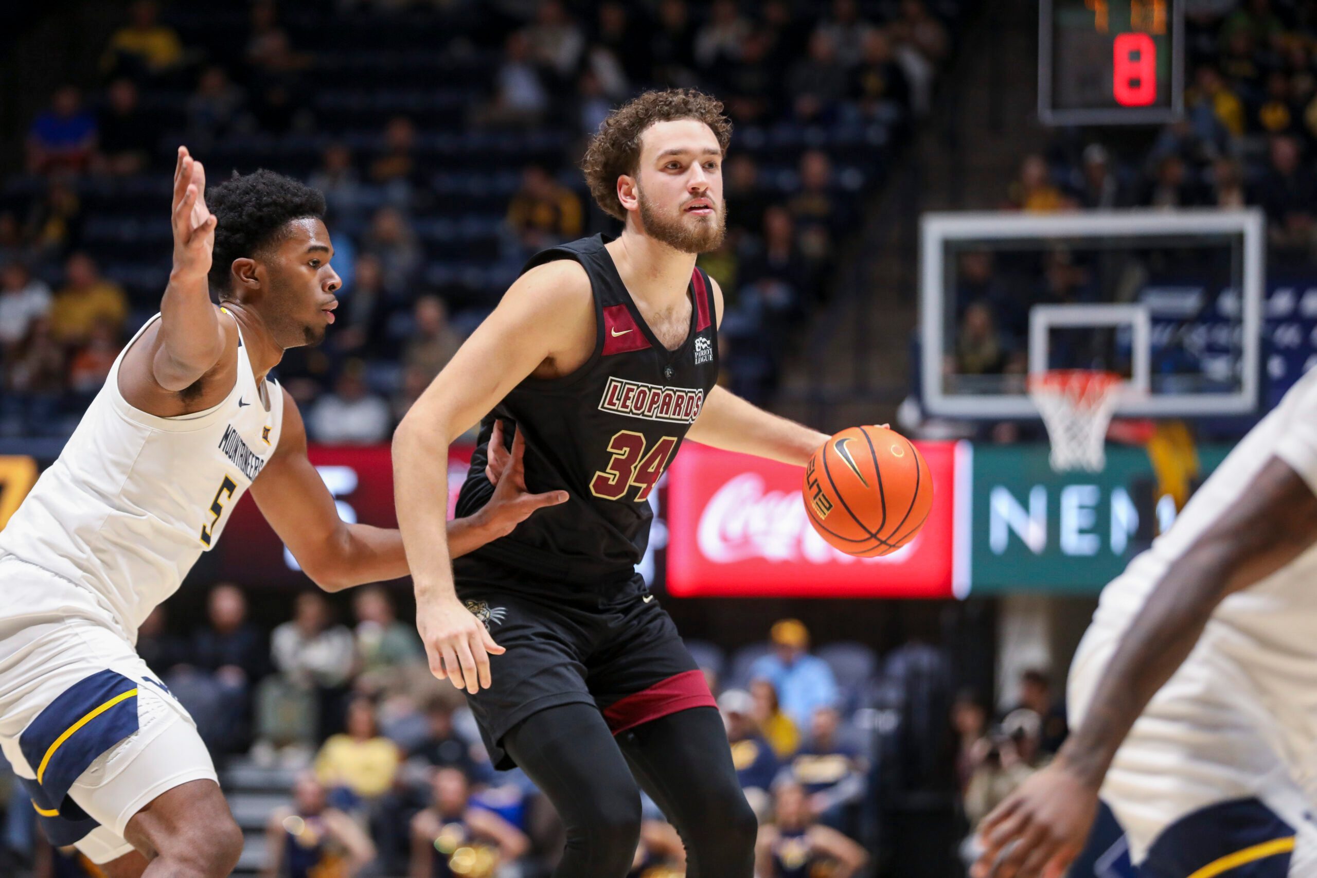 Nov 17, 2025; Morgantown, West Virginia, USA; Lafayette Leopards forward Luke Bevilacqua (34) dribbles against West Virginia Mountaineers forward DJ Thomas (5) during the first half at WVU Coliseum. Mandatory Credit: Ben Queen-Imagn Images