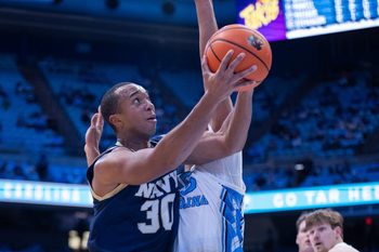 Nov 18, 2025; Chapel Hill, North Carolina, USA; Navy Midshipmen forward Mike Woods (30) shoots on North Carolina Tar Heels forward Jarin Stevenson (15) during the first half at Dean E. Smith Center. Mandatory Credit: Scott Kinser-Imagn Images