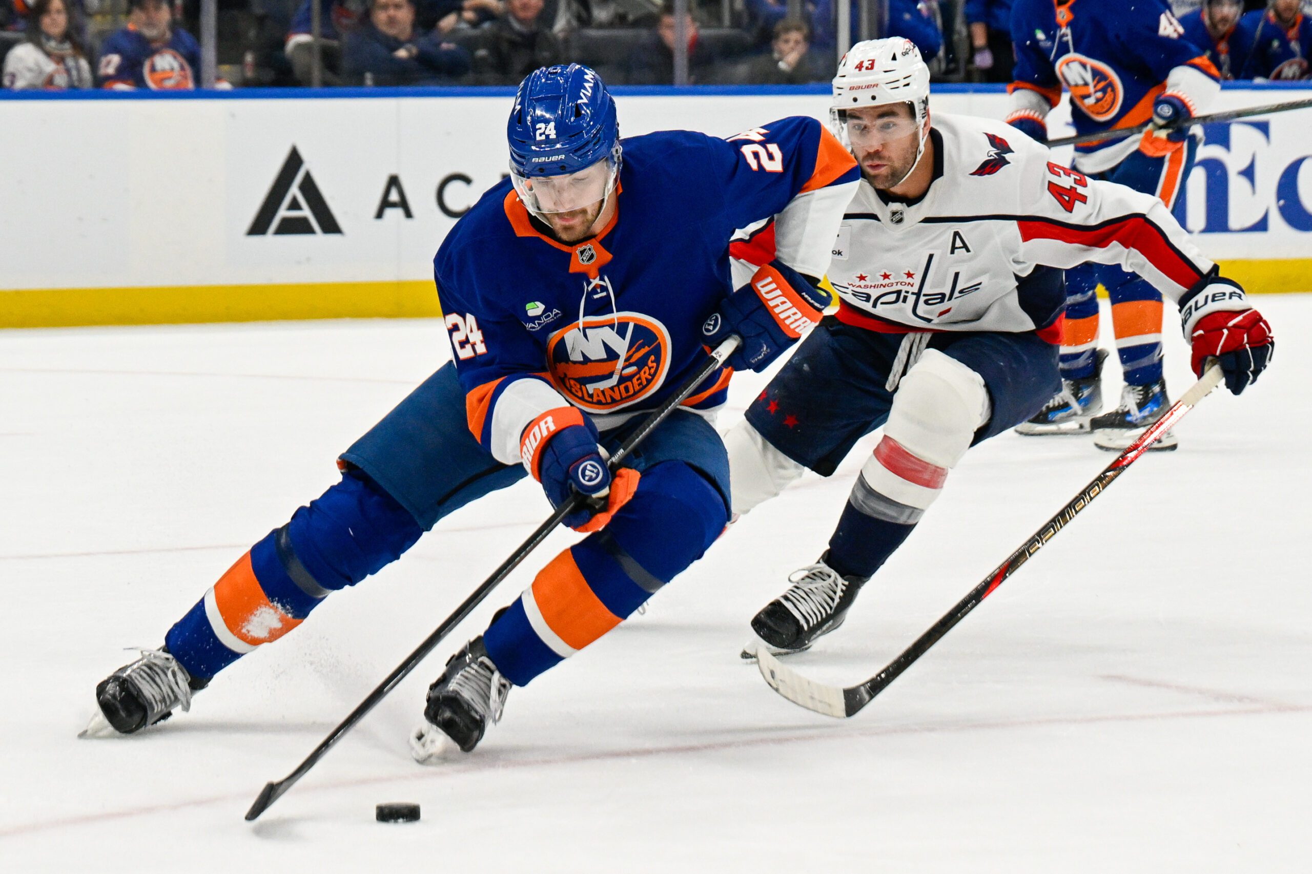 Nov 30, 2025; Elmont, New York, USA;  New York Islanders defenseman Scott Mayfield (24) skate with the puck chased by Washington Capitals right wing Tom Wilson (43) during the first period at UBS Arena. Mandatory Credit: Dennis Schneidler-Imagn Images