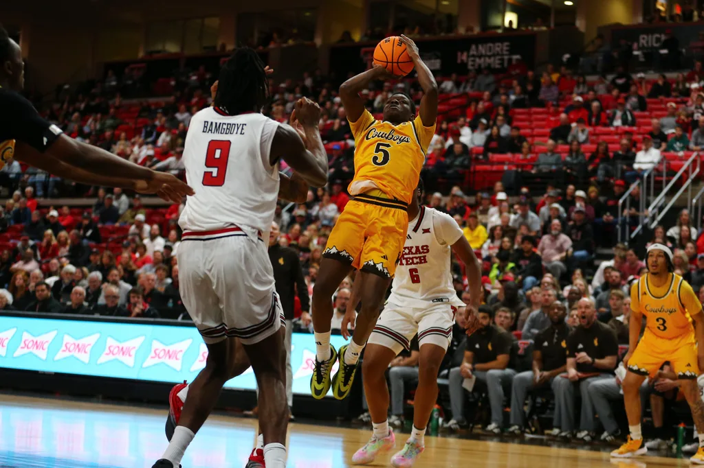 Nov 30, 2025; Lubbock, Texas, USA; Wyoming Cowboys guard Leland Walker (5) shoots a fadeaway shot against Texas Tech Red Raiders forward Luke Bamgboye (9) in the second half at United Supermarkets Arena. Mandatory Credit: Michael C. Johnson-Imagn Images