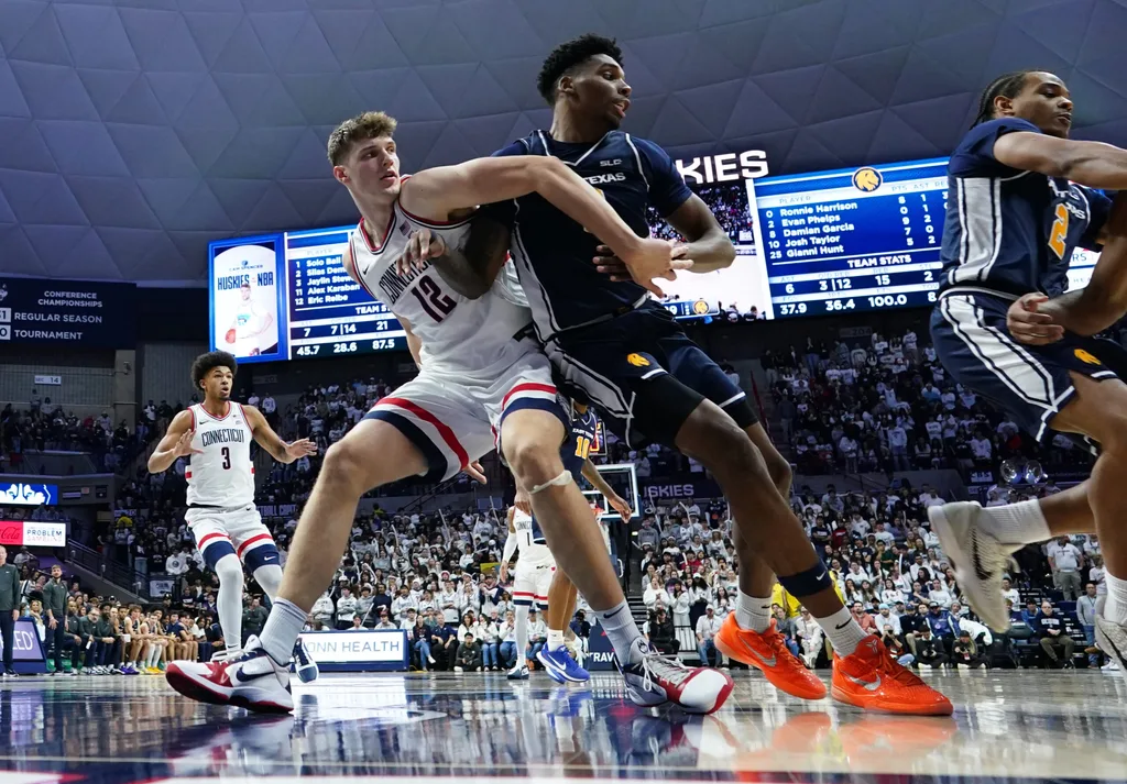 Dec 5, 2025; Storrs, Connecticut, USA; UConn Huskies center Eric Reibe (12) defends against East Texas A&M Lions forward Ronnie Harrison (0) in the second half at Harry A. Gampel Pavilion. Mandatory Credit: David Butler II-Imagn Images