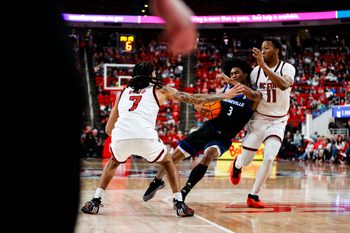 Dec 6, 2025; Raleigh, North Carolina, USA; UNC Asheville Bulldogs guard Kameron Taylor (3) is fouled on by NC State Wolfpack guard Alyn Breed (7) and guard Quadir Copeland (11) during the second half of the game at Lenovo Center. Mandatory Credit: Jaylynn Nash-Imagn Images