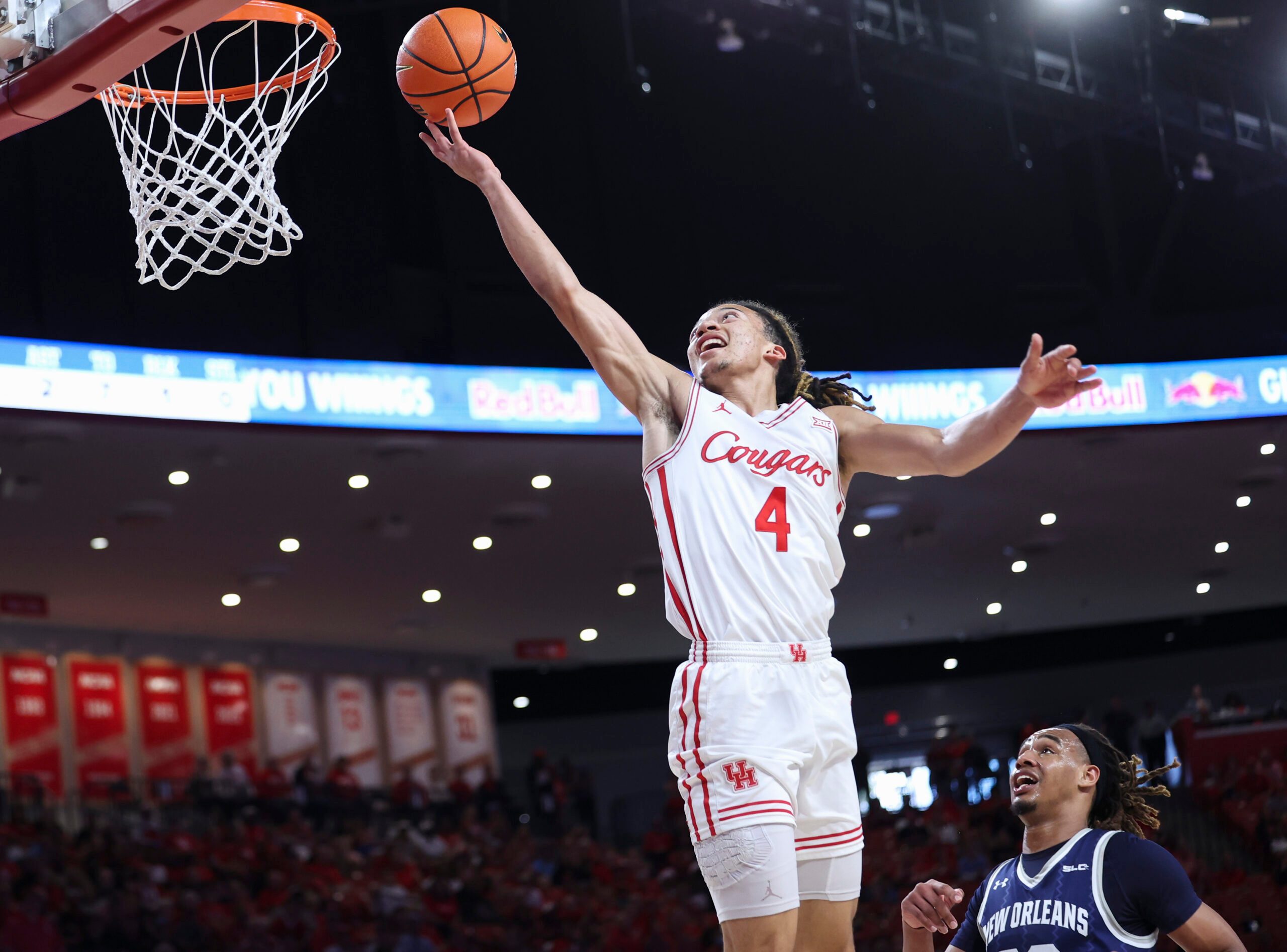Dec 13, 2025; Houston, Texas, USA; Houston Cougars guard Kingston Flemings (4) scores a basket as New Orleans Privateers forward MJ Thomas (23) defends during the first half at Fertitta Center. Mandatory Credit: Troy Taormina-Imagn Images