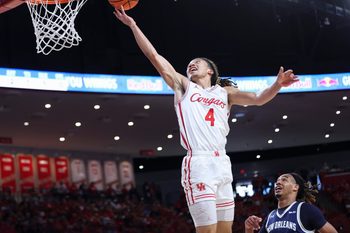 Dec 13, 2025; Houston, Texas, USA; Houston Cougars guard Kingston Flemings (4) scores a basket as New Orleans Privateers forward MJ Thomas (23) defends during the first half at Fertitta Center. Mandatory Credit: Troy Taormina-Imagn Images