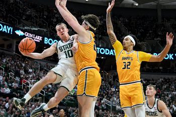 Dec 16, 2025; East Lansing, Michigan, USA; Michigan State Spartans guard Denham Wojcik (10) passes the ball around Toledo Rockets center Austin Parks (25) during the second half at Jack Breslin Student Events Center. Mandatory Credit: Dale Young-Imagn Images