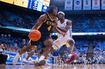 Dec 16, 2025; Chapel Hill, North Carolina, USA; ETSU Buccaneers guard Jaylen Smith (4) drives on North Carolina Tar Heels forward Caleb Wilson (8) during the first half at Dean E. Smith Center. Mandatory Credit: Scott Kinser-Imagn Images