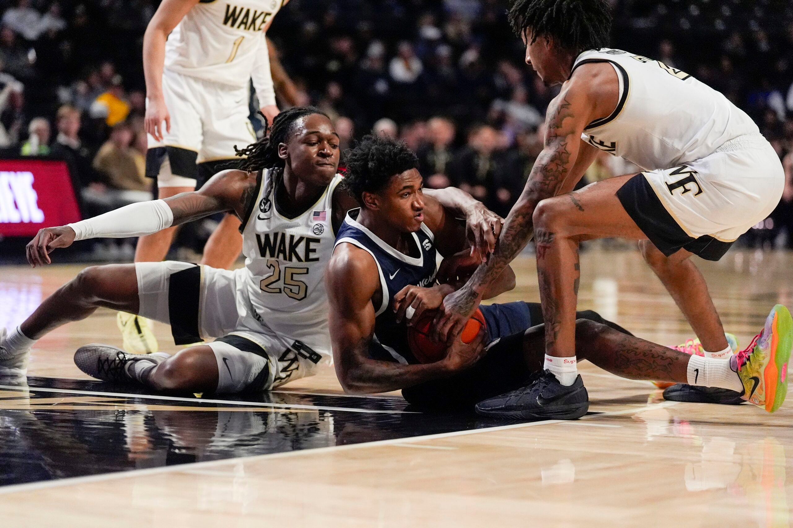 Dec 17, 2025; Winston-Salem, North Carolina, USA; Longwood Lancers forward Elijah Jones (23) tries to hold possession pressured by Wake Forest Demon Deacons forward Tre'Von Spillers (25) and guard Juke Harris (2) during the second half at Lawrence Joel Veterans Memorial Coliseum. Mandatory Credit: Jim Dedmon-Imagn Images