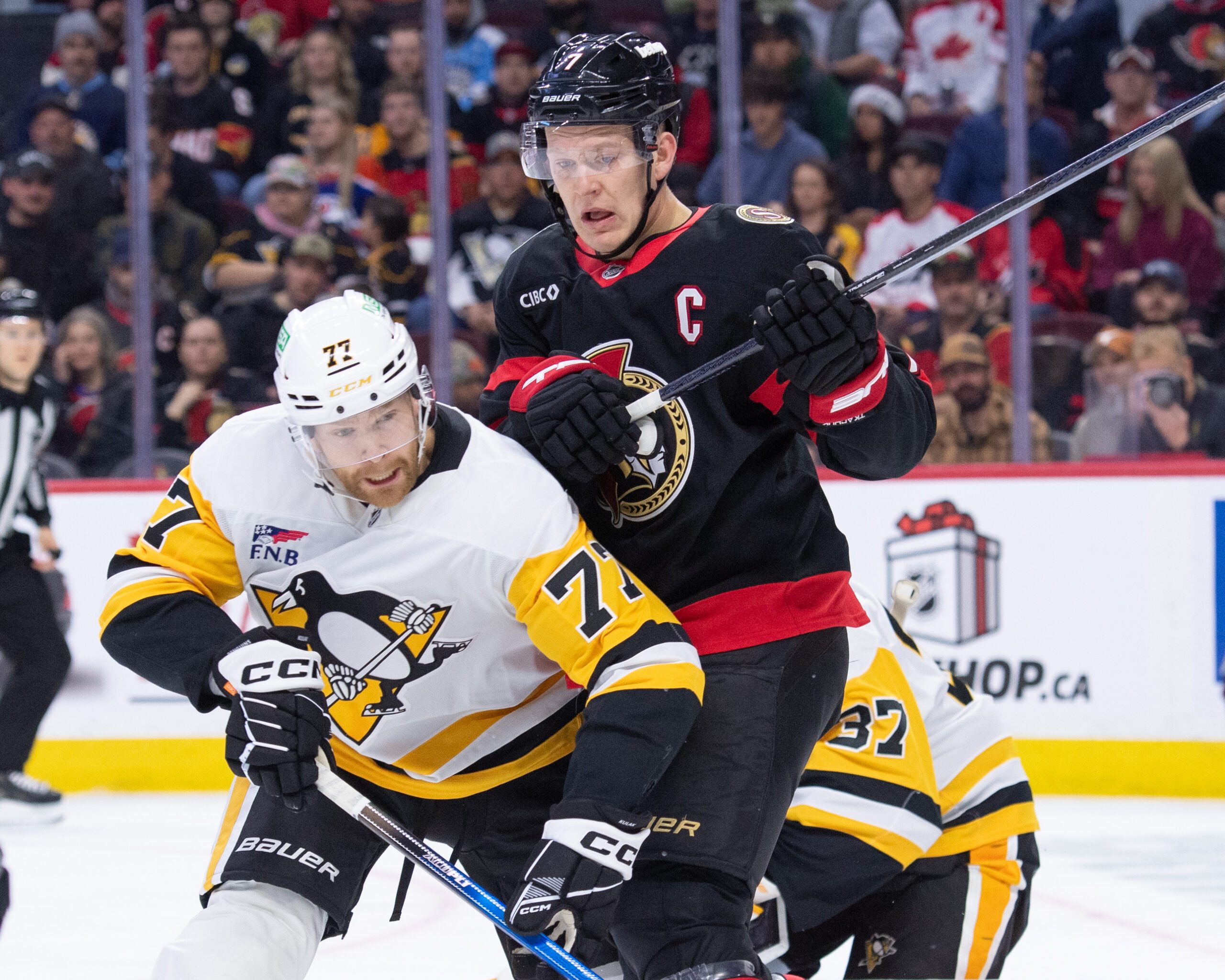 Dec 18, 2025; Ottawa, Ontario, CAN; Pittsburgh Penguins defenseman Brett Kulak (77) battles with Ottawa Senators left wing Brady Tkachuk (7) in the first period at the Canadian Tire Centre. Mandatory Credit: Marc DesRosiers-IMAGN Images