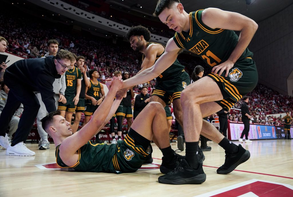 Dec 22, 2025; Bloomington, Indiana, USA; Siena Saints forward Brendan Coyle (21) and Siena Saints guard Justice Shoats (0) help up Siena Saints guard Gavin Doty (4) during the second half against the Indiana Hoosiers at Simon Skjodt Assembly Hall. Mandatory Credit: Robert Goddin-Imagn Images