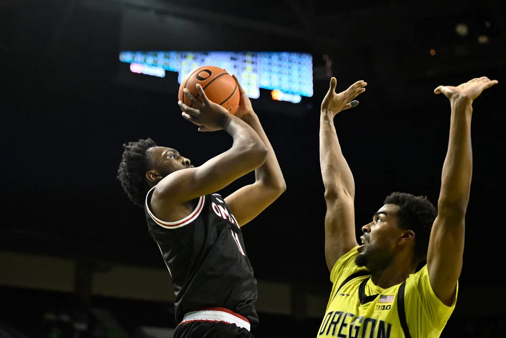 Dec 28, 2025; Eugene, Oregon, USA; Omaha Mavericks guard Paul Djobet (11) shoots the ball over Oregon Ducks forward Sean Stewart (13) during the second half at Matthew Knight Arena. Mandatory Credit: Craig Strobeck-Imagn Images