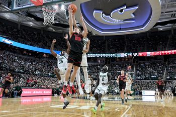 Dec 29, 2025; East Lansing, Michigan, USA;  Cornell Big Red guard Jake Fiegen (22) gets his layup blocked by Michigan State Spartans forward Jordan Scott (6) during the first half at Jack Breslin Student Events Center. Mandatory Credit: Dale Young-Imagn Images