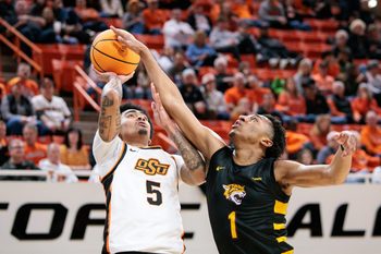 Dec 29, 2025; Stillwater, Oklahoma, USA; Bethune-Cookman Wildcats player Arterio Morris blocks a shot by Oklahoma State Cowboys player Vyctorius Miller during the first half at Gallagher-Iba Arena. Mandatory Credit: William Purnell-Imagn Images