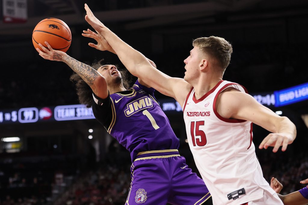 Dec 29, 2025; Fayetteville, Arkansas, USA; James Madison Dukes guard Paul Jones III (1) is fouled while shooting by Arkansas Razorbacks center Elmir Dzafic (15) during the second half at Bud Walton Arena. Arkansas won 103-74. Mandatory Credit: Nelson Chenault-Imagn Images