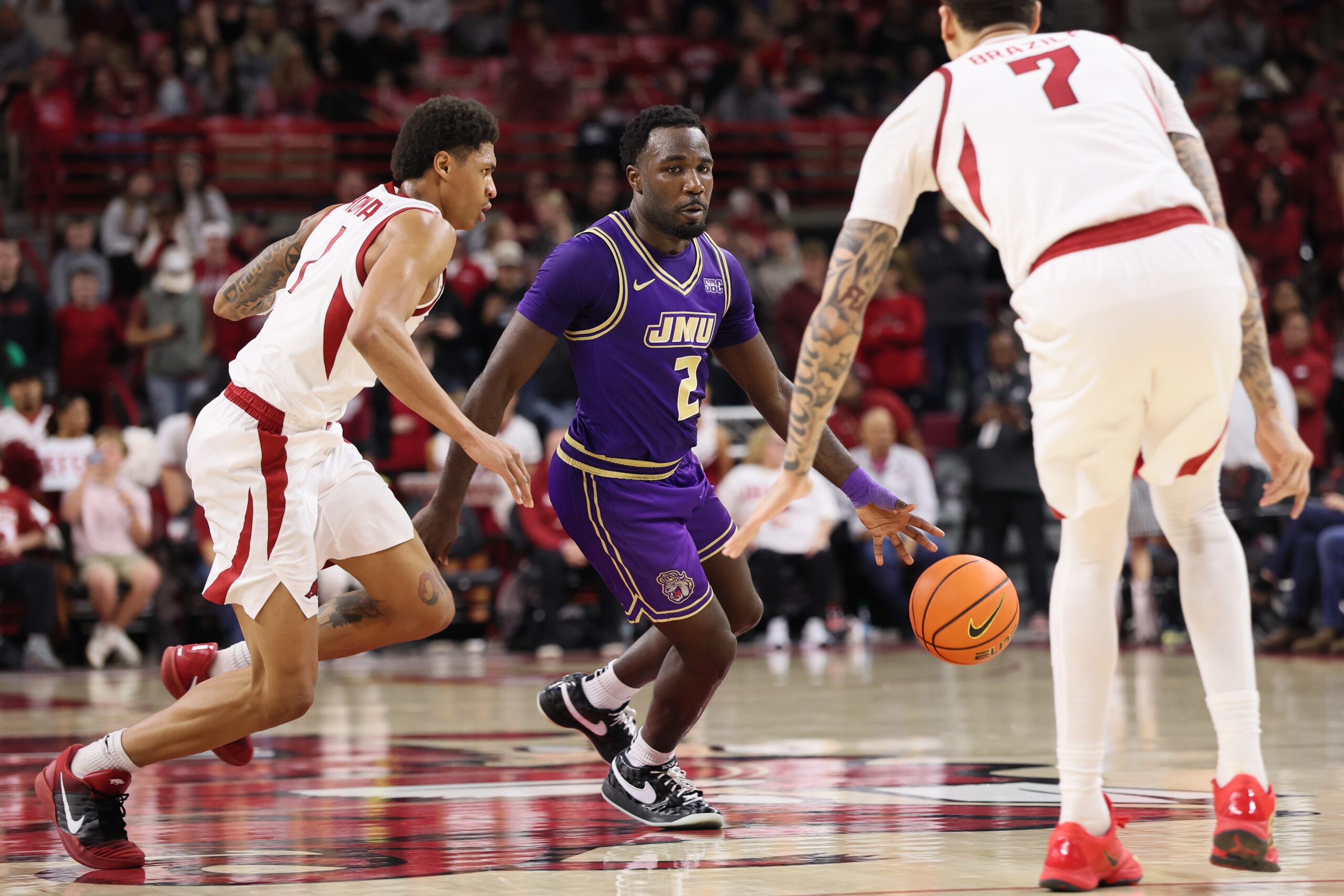 Dec 29, 2025; Fayetteville, Arkansas, USA; James Madison Dukes guard Bradley Douglas (2) drives against Arkansas Razorbacks guard Meleek Thomas (1) during the second half at Bud Walton Arena. Arkansas won 103-74. Mandatory Credit: Nelson Chenault-Imagn Images