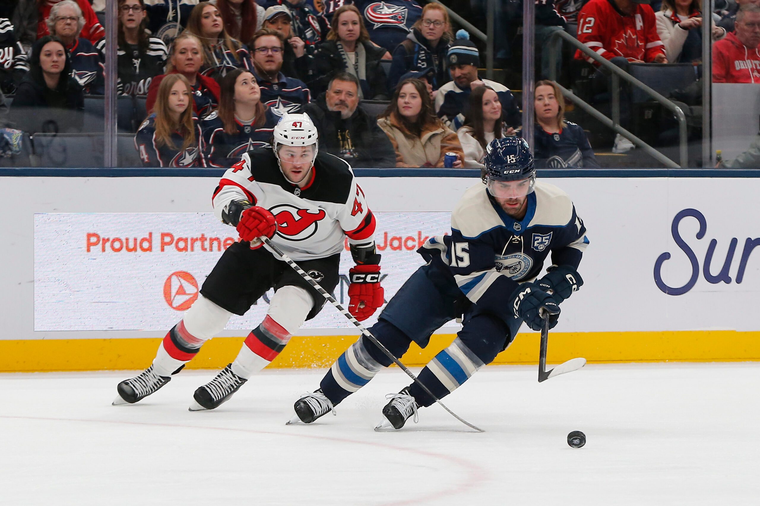 Dec 31, 2025; Columbus, Ohio, USA; Columbus Blue Jackets defenseman Dante Fabbro (15) carries the puck away from New Jersey Devils left wing Paul Cotter (47) during the third period at Nationwide Arena. Mandatory Credit: Russell LaBounty-Imagn Images
