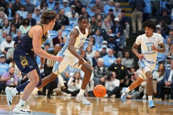 Jan 21, 2026; Chapel Hill, North Carolina, USA; North Carolina Tar Heels forward Caleb Wilson (8) brings the ball up the court as Notre Dame Fighting Irish forward Ryder Frost (7) defends in the second half at Dean E. Smith Center. Mandatory Credit: Bob Donnan-Imagn Images