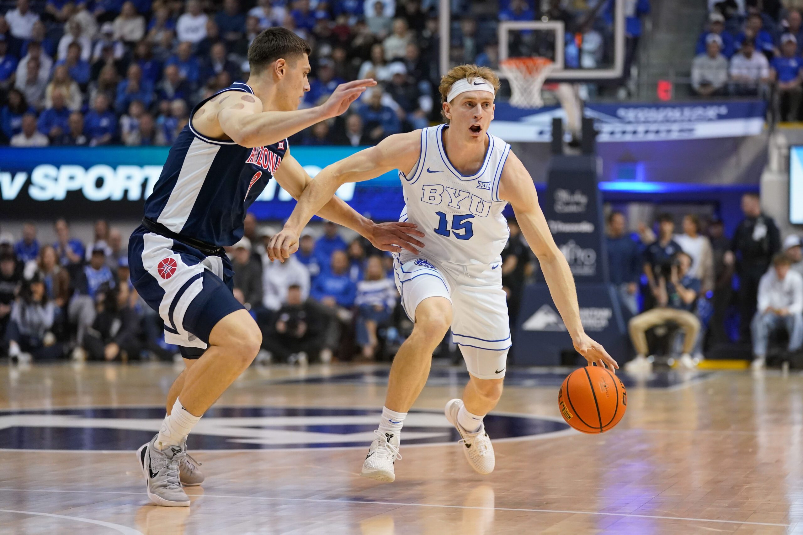 Jan 26, 2026; Provo, Utah, USA; BYU Cougars guard Richie Saunders (15) controls the ball while being defended by Arizona Wildcats forward Ivan Kharchenkov (8) during the first half at Marriott Center. Mandatory Credit: Aaron Baker-Imagn Images