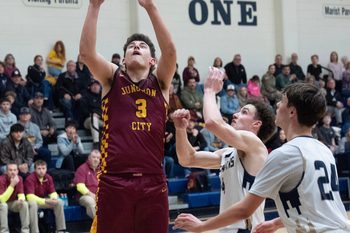 Boys basketball Junction City’s Kaden Shafer, left, shots ahead of Marist Catholic’s Gianni Lombardi and Fletcher Pollard, right, during the second half in Eugene Feb. 3, 2026.
