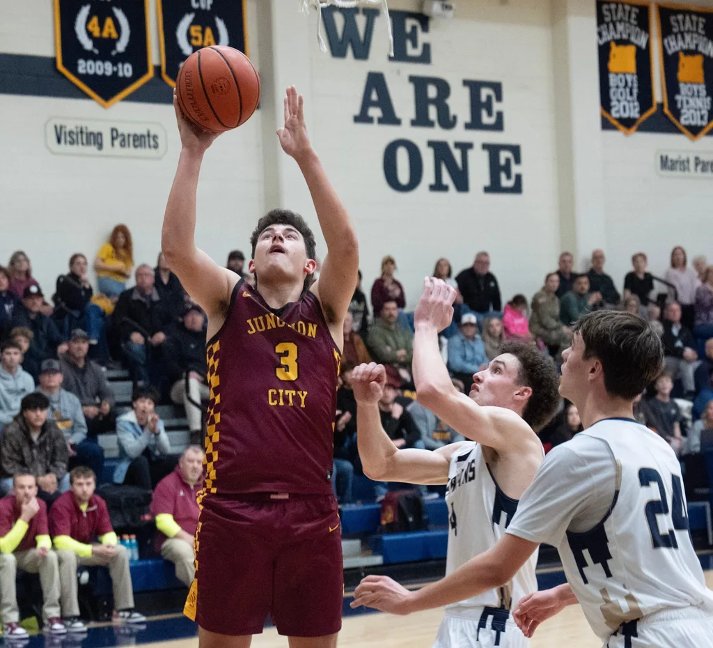 Boys basketball Junction City’s Kaden Shafer, left, shots ahead of Marist Catholic’s Gianni Lombardi and Fletcher Pollard, right, during the second half in Eugene Feb. 3, 2026.