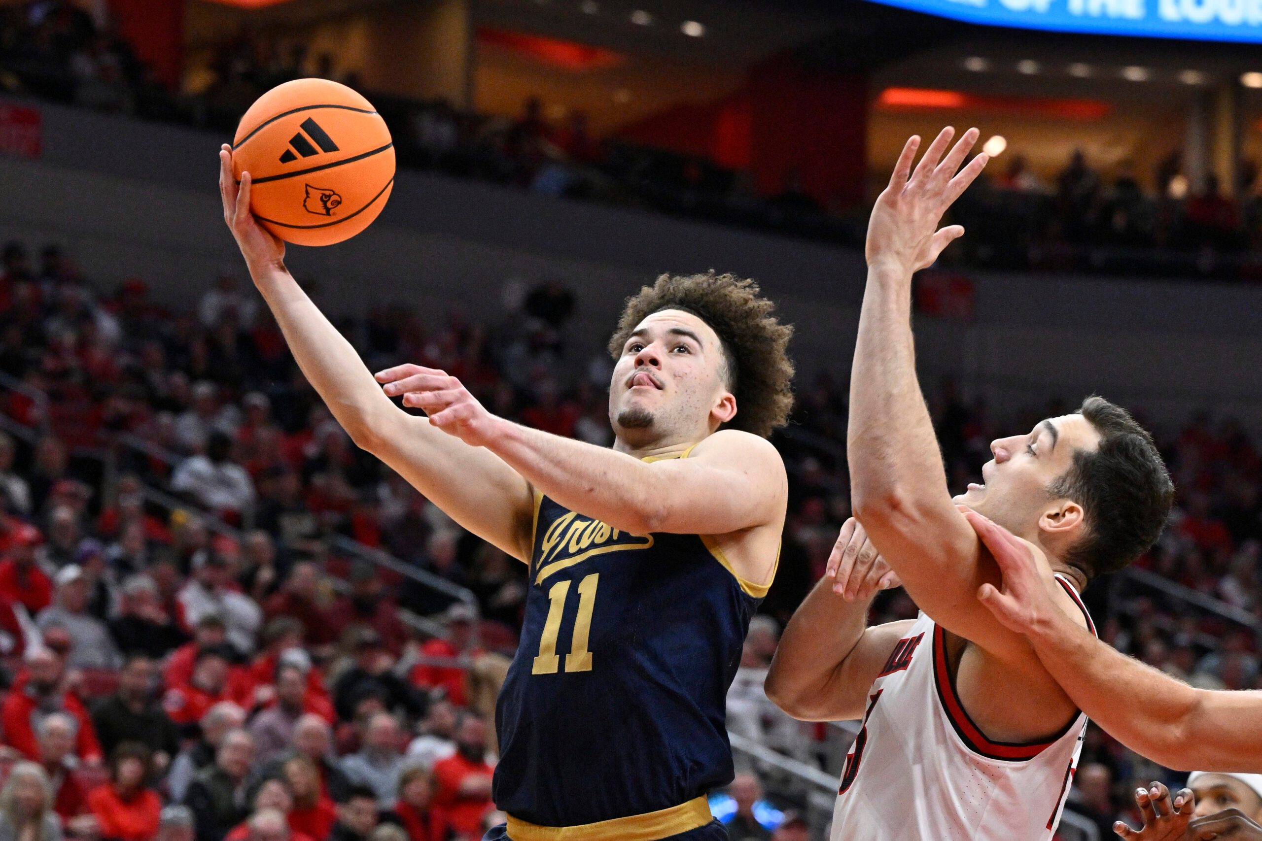Feb 4, 2026; Louisville, Kentucky, USA;  Notre Dame Fighting Irish guard Braeden Shrewsberry (11) shoots against Louisville Cardinals forward Vangelis Zougris (53) during the first half at KFC Yum! Center. Mandatory Credit: Jamie Rhodes-Imagn Images