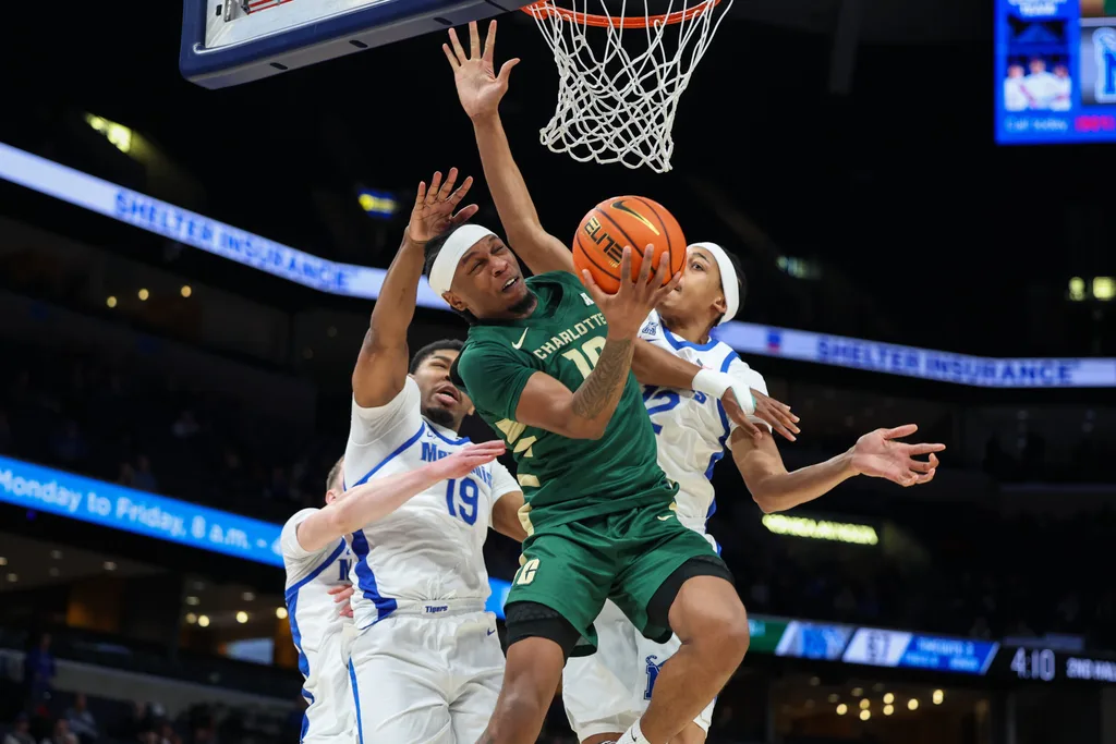 Feb 8, 2026; Memphis, Tennessee, USA; Charlotte 49ers guard Damoni Harrison (10) shoots the ball against Memphis Tigers forward Tariq Ingraham (19) and forward William Wharton (12) during the second half at FedExForum. Mandatory Credit: Wesley Hale-Imagn Images