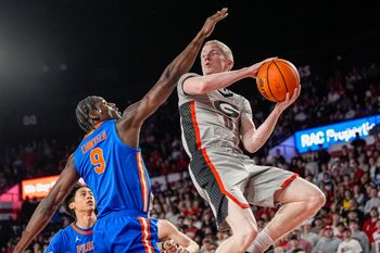 Feb 11, 2026; Athens, Georgia, USA; Georgia Bulldogs guard Blue Cain (0) looks to pass against Florida Gators center Rueben Chinyelu (9) during the first half at Stegeman Coliseum. Mandatory Credit: Dale Zanine-Imagn Images