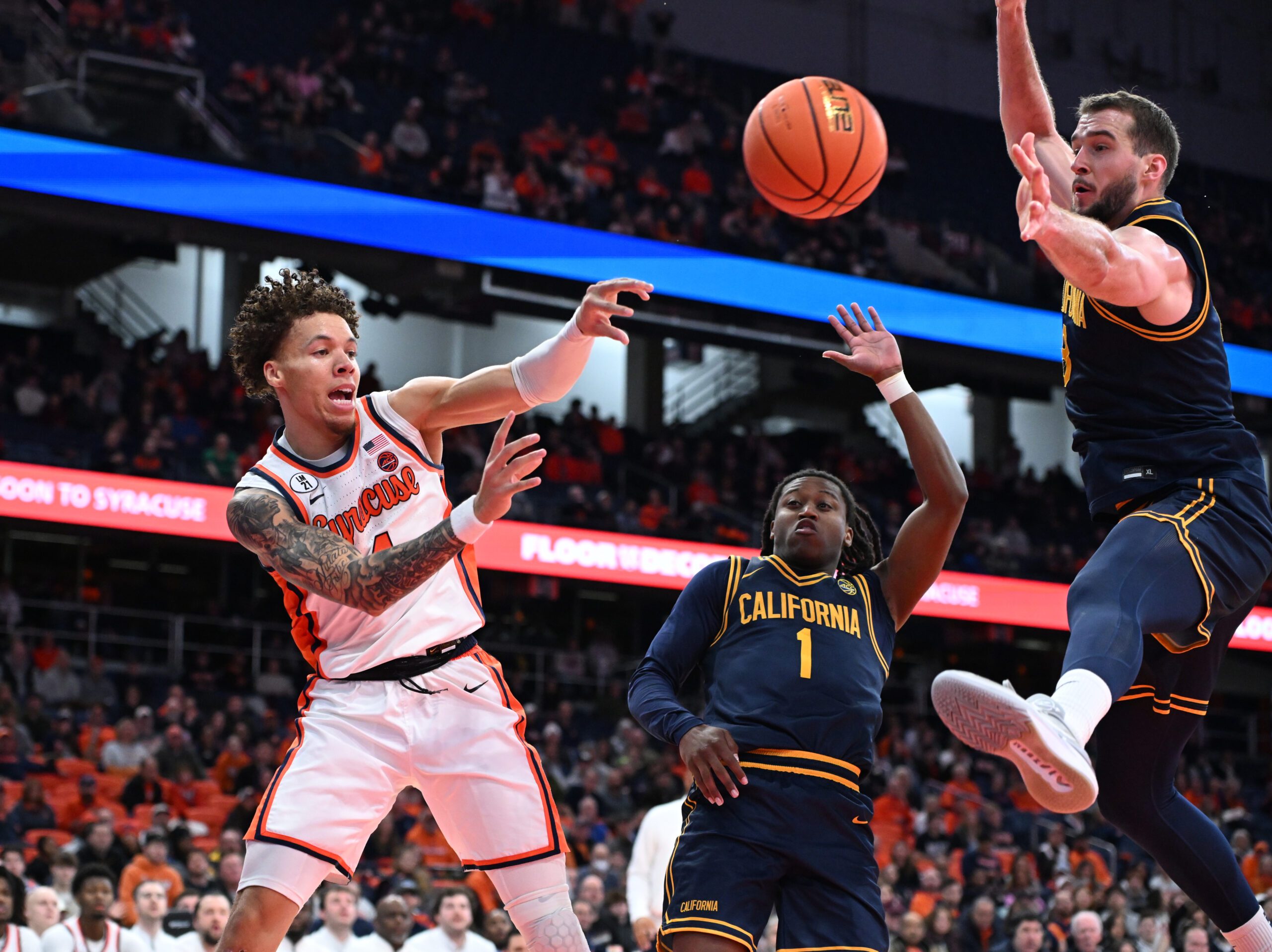 Feb 11, 2026; Syracuse, New York, USA; Syracuse Orange guard Nate Kingz (4) passes the ball as California Golden Bears center Milos Ilic (8) and guard Dejuan Campbell (1) defend in the second half at the JMA Wireless Dome. Mandatory Credit: Mark Konezny-Imagn Images