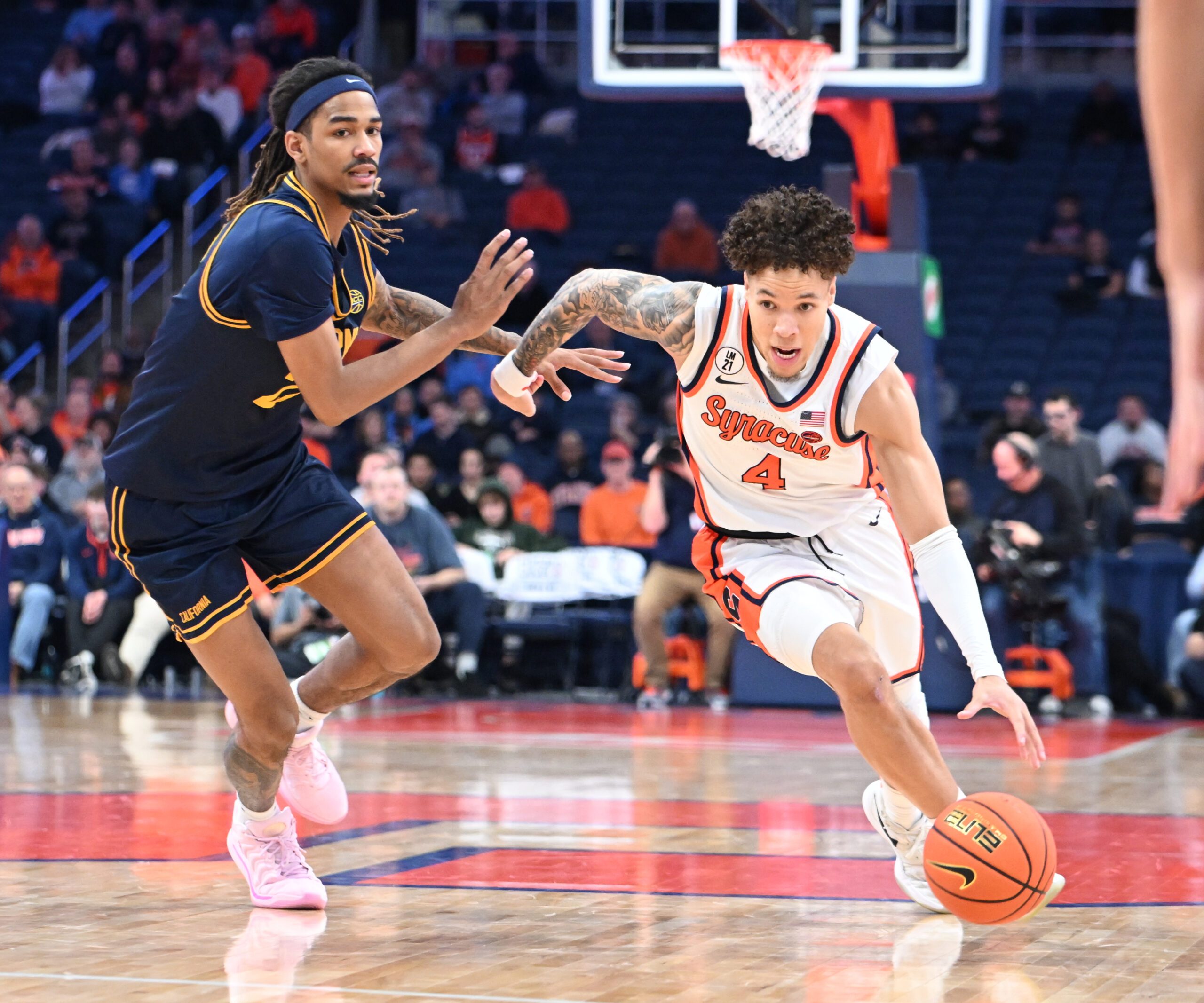 Feb 11, 2026; Syracuse, New York, USA; Syracuse Orange guard Nate Kingz (4) drives past California Golden Bears forward Chris Bell (22) in the second half at the JMA Wireless Dome. Mandatory Credit: Mark Konezny-Imagn Images