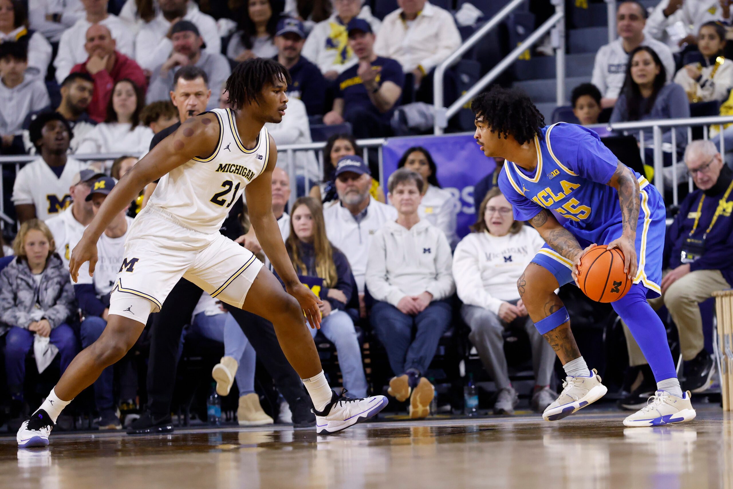 Feb 14, 2026; Ann Arbor, Michigan, USA; UCLA Bruins guard Skyy Clark (55) is defended by Michigan Wolverines forward Morez Johnson Jr. (21) in the first half at Crisler Center. Mandatory Credit: Rick Osentoski-Imagn Images