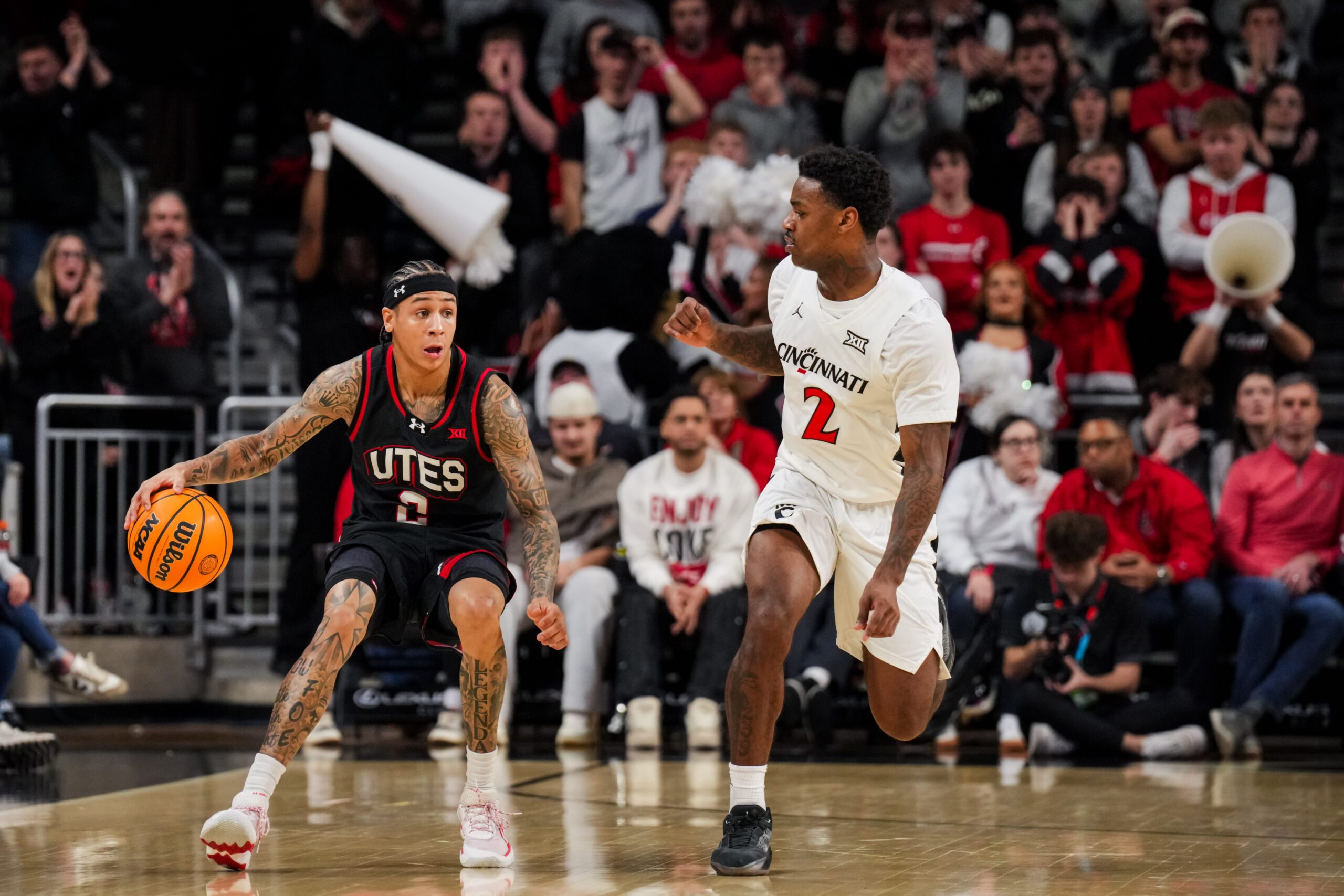 Feb 15, 2026; Cincinnati, Ohio, USA;  Utah Utes guard Terrence Brown (2) dribbles the ball against Cincinnati Bearcats guard Jizzle James (2) in the second at Fifth Third Arena. Mandatory Credit: Aaron Doster-Imagn Images