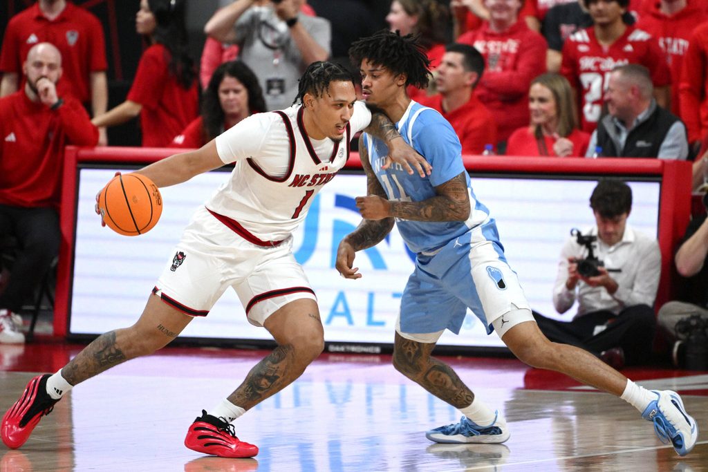 Feb 17, 2026; Raleigh, North Carolina, USA; NC State Wolfpack forward Darrion Williams (1) drives the ball to the basket against North Carolina Tar Heels guard Jonathan Powell (11) during the second half at Lenovo Center. Mandatory Credit: Zachary Taft-Imagn Images