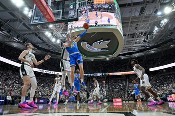 Feb 17, 2026; East Lansing, Michigan, USA; UCLA Bruins forward Tyler Bilodeau (34) tries a reverse shot off the glass during the first half against the Michigan State Spartans at Jack Breslin Student Events Center. Mandatory Credit: Dale Young-Imagn Images
