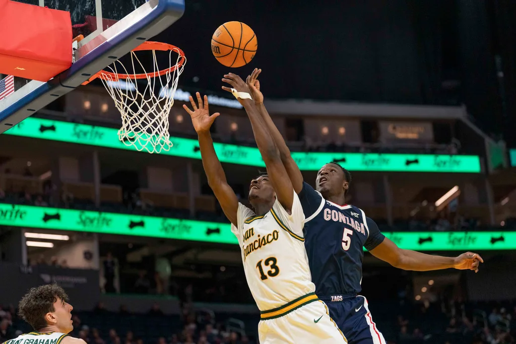 Feb 18, 2026; San Francisco, California, USA; San Francisco Dons guard Legend Smiley (13) and Gonzaga Bulldogs forward Emmanuel Innocenti (5) reach for the ball during the second half at Chase Center. Mandatory Credit: Stan Szeto-Imagn Images