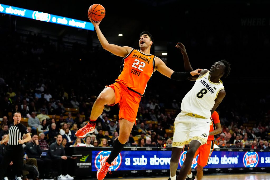 Feb 21, 2026; Boulder, Colorado, USA; Oklahoma State Cowboys center Parsa Fallah (22) finishes off a basket past Colorado Buffaloes forward Bangot Dak (8) in the first half at the CU Events Center. Mandatory Credit: Ron Chenoy-Imagn Images