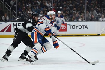 Feb 26, 2026; Los Angeles, California, USA; Edmonton Oilers center Connor McDavid (97) and Los Angeles Kings right wing Alex Laferriere (14) battle for the puck during the second period at Crypto.com Arena. Mandatory Credit: Griffin Hooper-Imagn Images