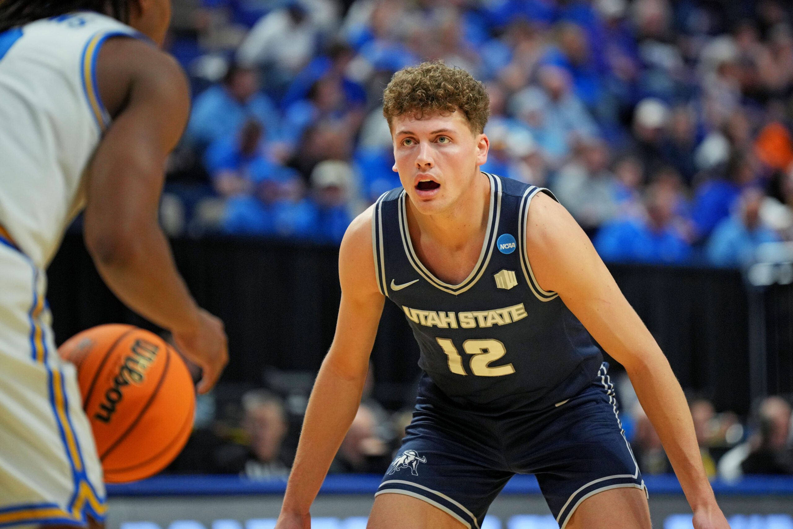Mar 20, 2025; Lexington, KY, USA;  Utah State Aggies guard Mason Falslev (12) guards UCLA Bruins guard Dylan Andrews (2) in the first round of the NCAA Tournament at Rupp Arena. Mandatory Credit: Aaron Doster-Imagn Images