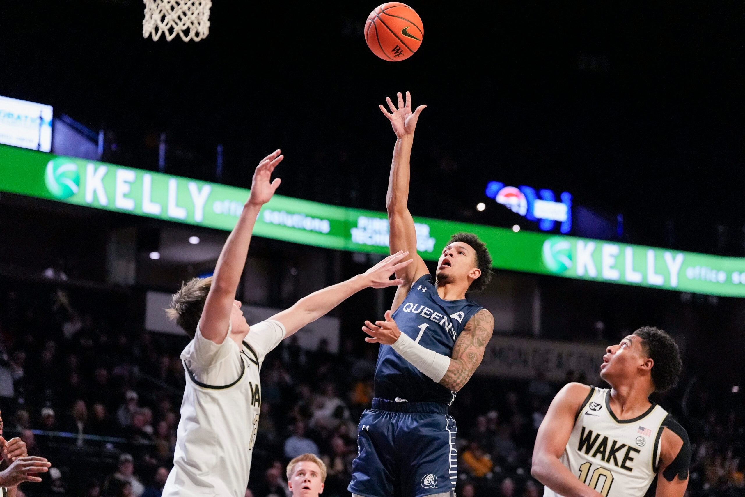 Dec 14, 2025; Winston-Salem, North Carolina, USA;  Queens University Royals guard Nasir Mann (1) shoots the ball against Wake Forest Demon Deacons guard Isaac Carr (7) during the second half at Lawrence Joel Veterans Memorial Coliseum. Mandatory Credit: Jim Dedmon-Imagn Images