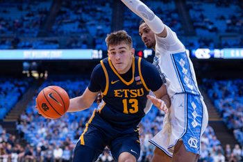 Dec 16, 2025; Chapel Hill, North Carolina, USA; ETSU Buccaneers forward Blake Barkley (13) drives on North Carolina Tar Heels forward Jarin Stevenson (15) during the first half at Dean E. Smith Center. Mandatory Credit: Scott Kinser-Imagn Images