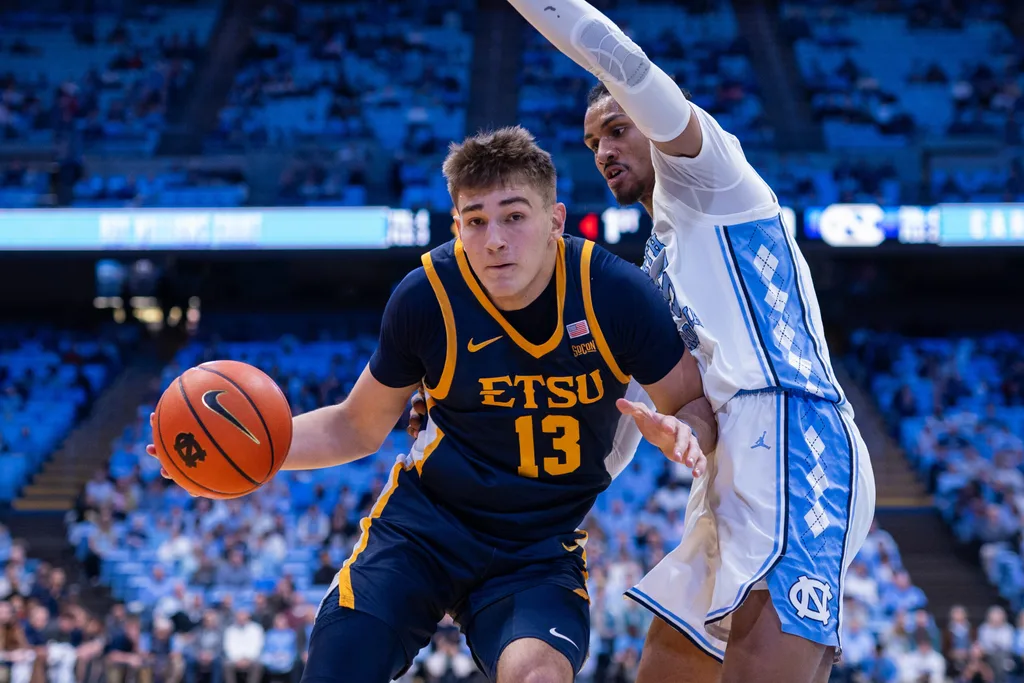 Dec 16, 2025; Chapel Hill, North Carolina, USA; ETSU Buccaneers forward Blake Barkley (13) drives on North Carolina Tar Heels forward Jarin Stevenson (15) during the first half at Dean E. Smith Center. Mandatory Credit: Scott Kinser-Imagn Images