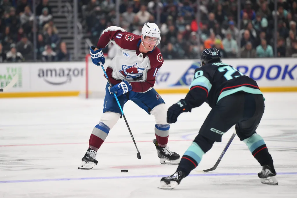 Dec 16, 2025; Seattle, Washington, USA; Colorado Avalanche center Brock Nelson (11) plays the puck while defended by Seattle Kraken right wing Eeli Tolvanen (20) during the third period at Climate Pledge Arena. Mandatory Credit: Steven Bisig-Imagn Images
